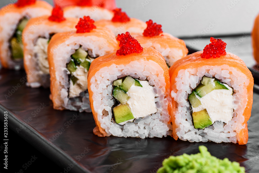 Philadelphia roll with salmon and cucumber. Maki Sushi set on dark pattern background. Sushi Set nigiri, rolls and sashimi served in black square plate. On dark pattern background. Philadelphia roll with salmon and cucumber. Maki Sushi set on dark pattern background. Sushi Set nigiri, rolls and sashimi served in black square plate. On dark pattern background.