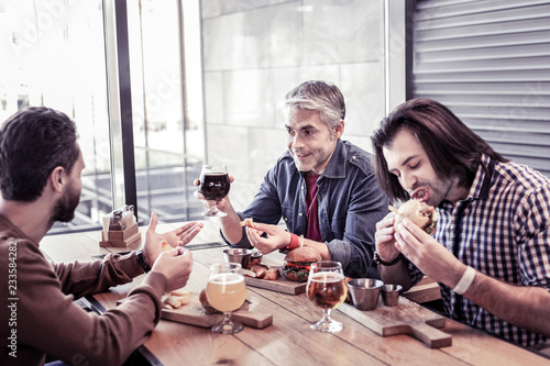 Cheerful males talking about hobbies during pause