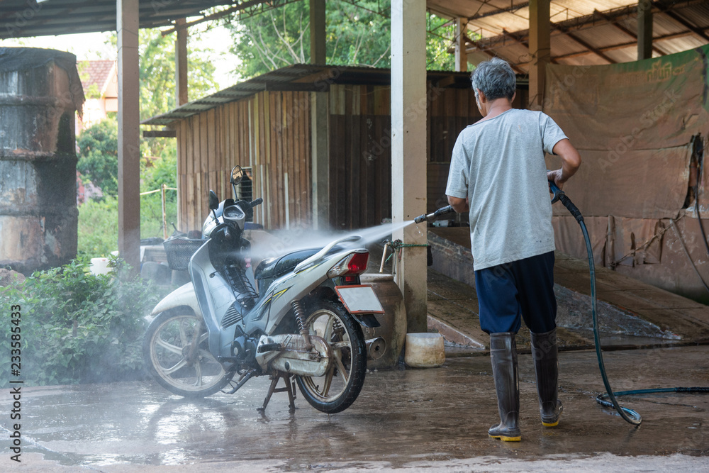 Old man wash your motorcycle with High Pressure Washer at car wash shop Old man wash your motorcycle with High Pressure Washer at car wash shop