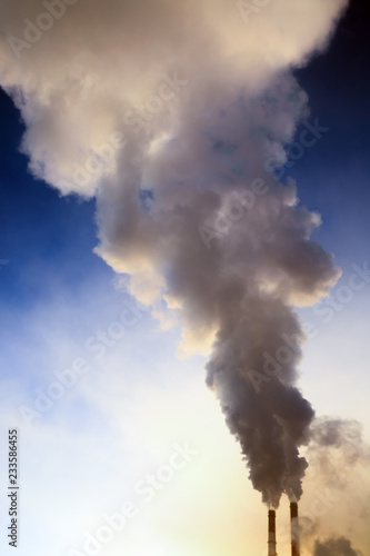 Smoke from factory pipes against blue sky. Concept of oil and gas processing plants, coal mining and minerals