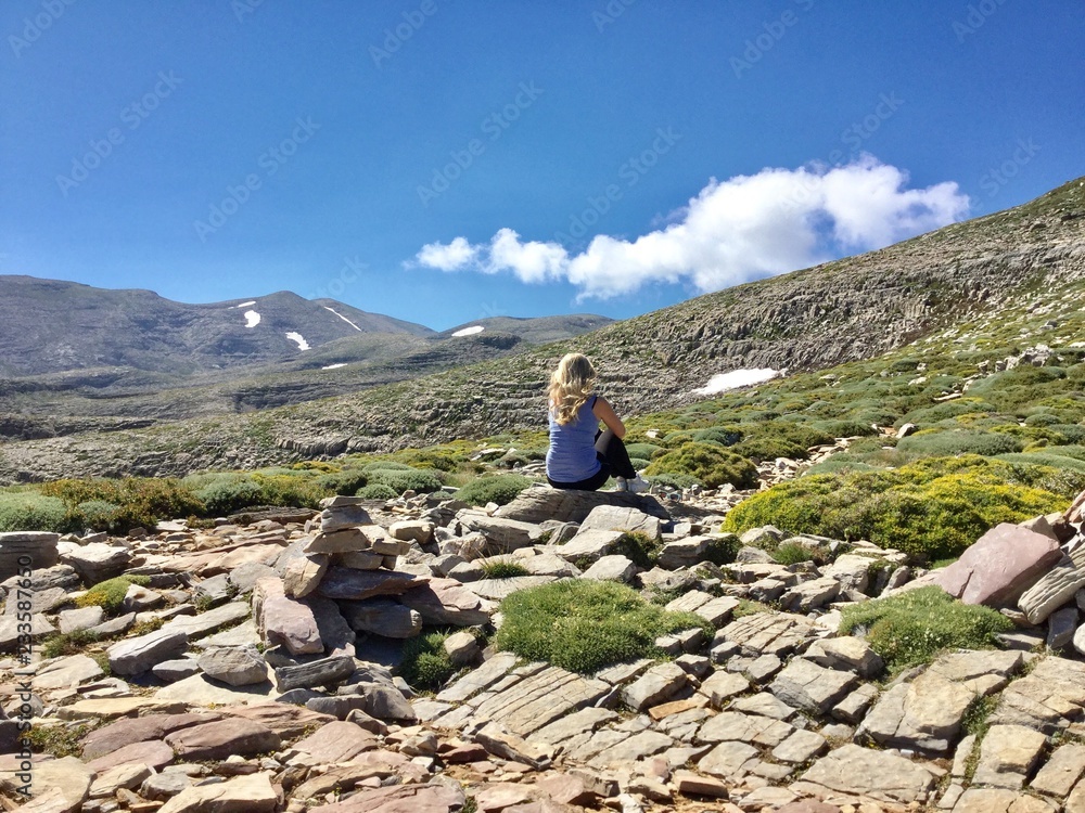 blond girl sitting in the mountains