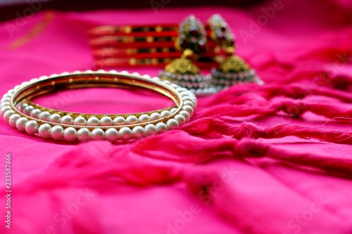 Indian ethnic jewelry bracelets and earrings on pink fabric