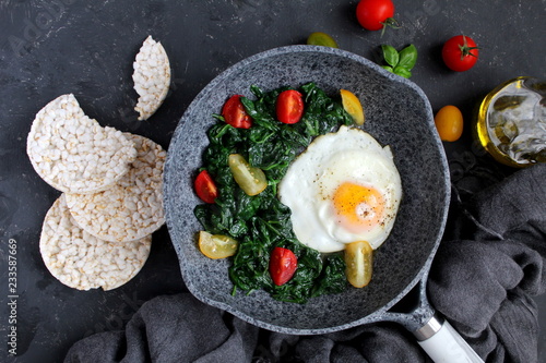 Billede på lærred Fried eggs with spinach and tomato on iron pan