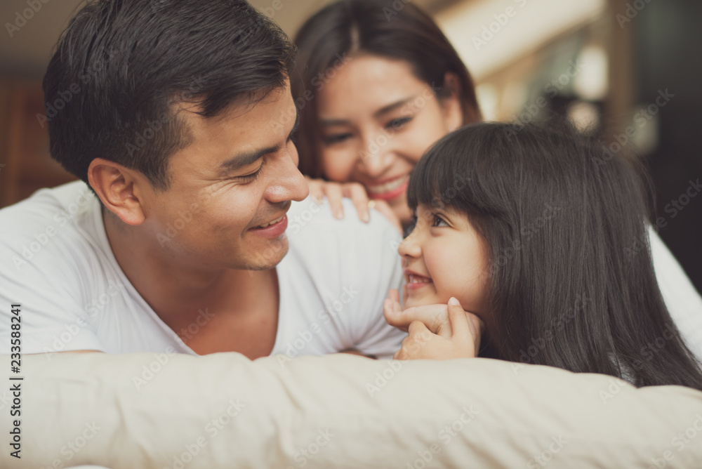 Young mother father and daughter enjoying with lie on the stomach in the bed with pillow, happy family smiling at home. Young mother father and daughter enjoying with lie on the stomach in the bed with pillow, happy family smiling at home.