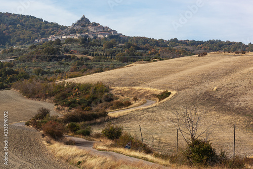 The curved country road through arable fields to the medieval castle-town in Tuscany, Italy