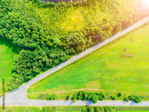 Aerial view of a country road in the forest with moving cars. Landscape. Captured from above with a drone. Aerial bird's eye road with car. Aerial top view forest. Texture of forest view from above.