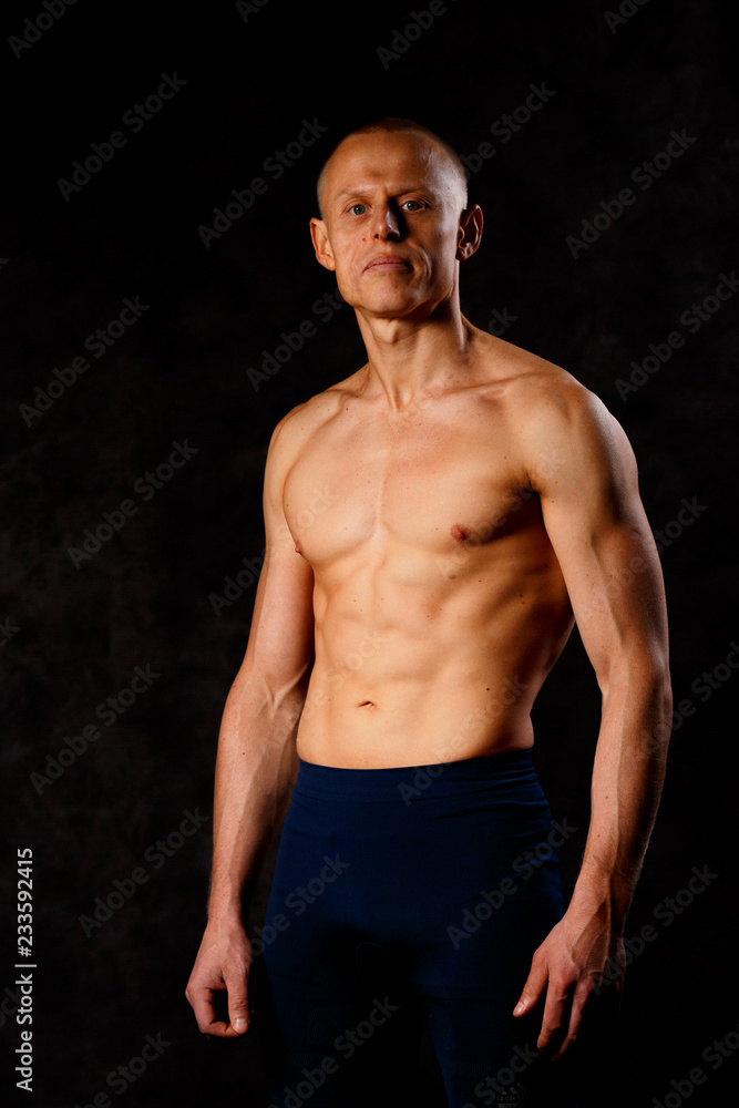 Muscular model sports young man on a dark background. Portrait of sporty healthy strong muscle guy. Sexy torso.