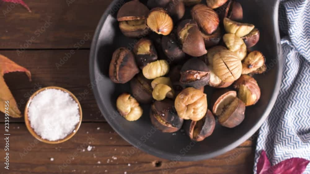 Roasted chestnuts in cast iron pan over rustic wooden board and grey wooden background, selective focus. Roasted chestnuts in cast iron pan over rustic wooden board and grey wooden background, selective focus.