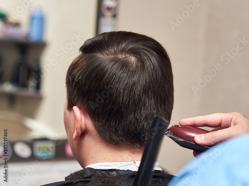 Hairdresser making a haircut to man with clipper.