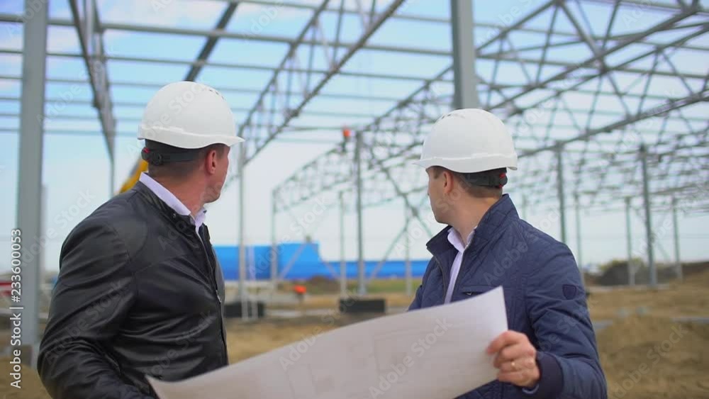male engineers supervisors in hard hats working with drawing blueprint and discussing plan. They checking quality of object on construction site. Businessman engineer architects builders architect man male engineers supervisors in hard hats working with drawing blueprint and discussing plan. They checking quality of object on construction site. Businessman engineer architects builders architect man