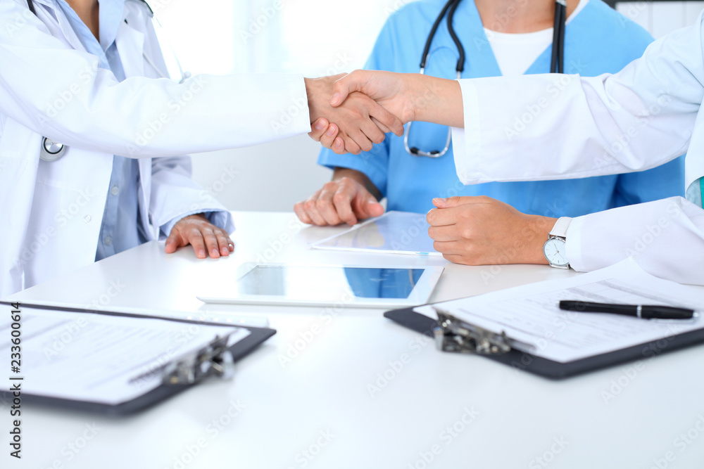 Two doctors shaking hands to each other at meeting. Teamwork and agreement in medicine Two doctors shaking hands to each other at meeting. Teamwork and agreement in medicine