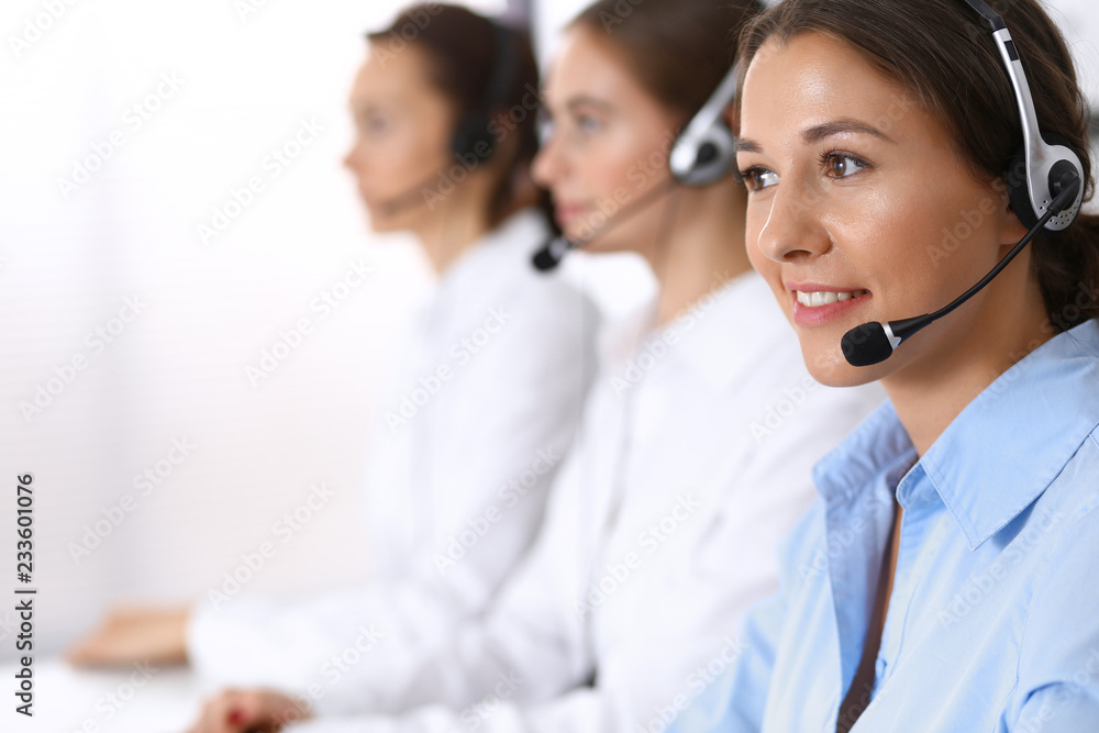 Call center. Group of operators at work. Focus at beautiful business woman in headset Call center. Group of operators at work. Focus at beautiful business woman in headset