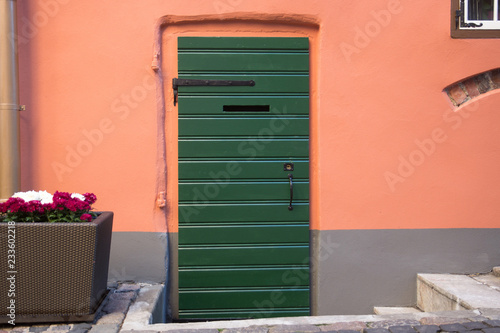a green wooden door in orange wall