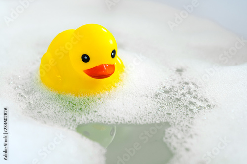 Foto One yellow rubber duck with soap bubble bath, light  background with bubbles