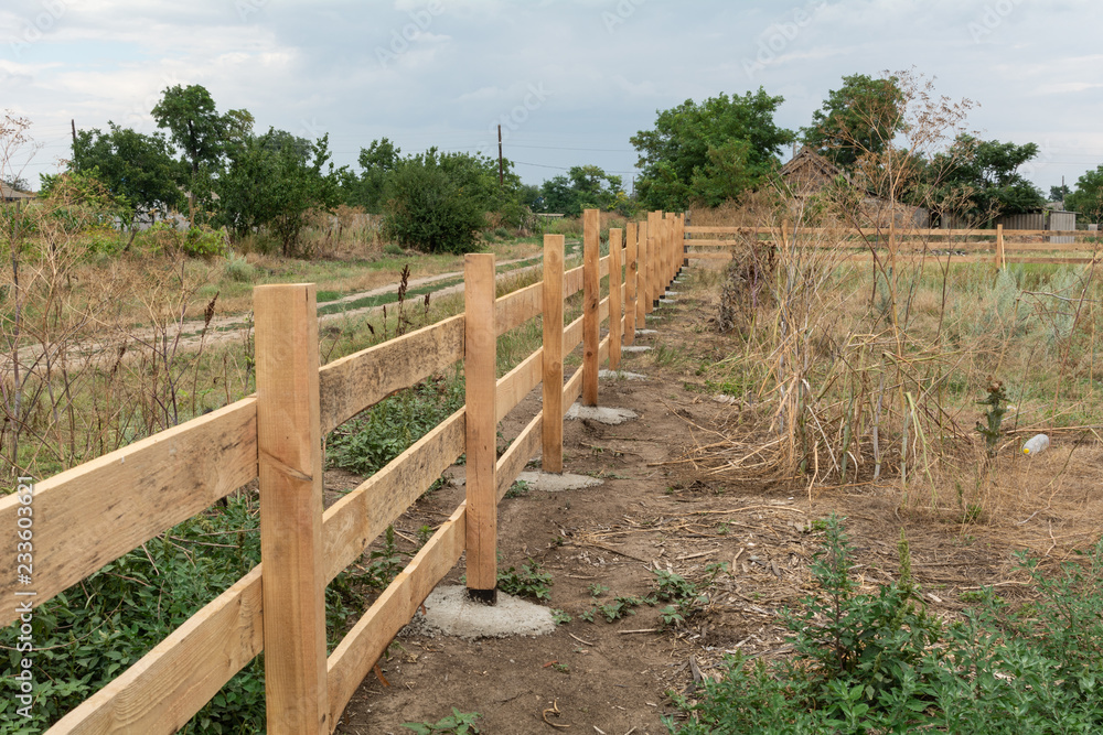 Ranch style fence. Rural wooden fence on green grass at farm ranch land in Shagany, Ukraina.