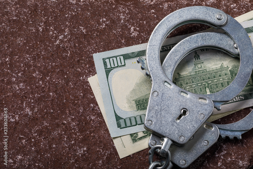 Dollars and handcuffs on a stone surface with copy space, top view Dollars and handcuffs on a stone surface with copy space, top view