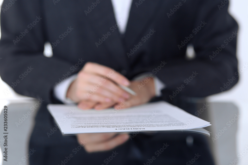 Close-up of female hands with pen over document, business concept. Lawyer or business woman at work in office Close-up of female hands with pen over document, business concept. Lawyer or business woman at work in office