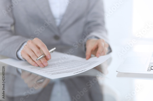 Close-up of female hands with pen over document, business concept. Lawyer or business woman at work in office