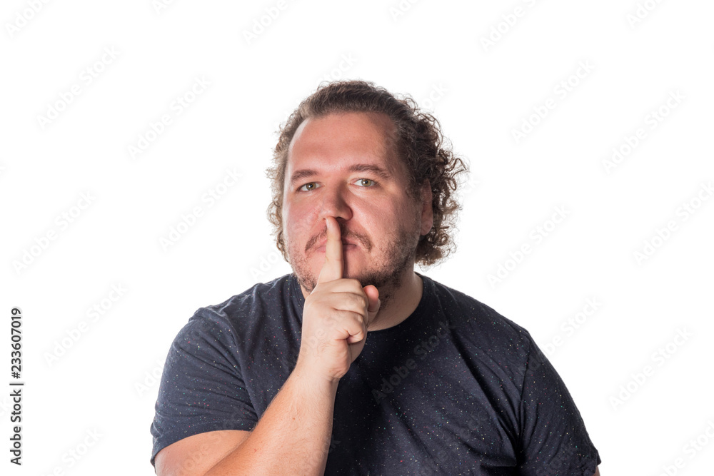 Portrait of handsome man cowering his mouth with his finger and looking at camera while standing against white background Portrait of handsome man cowering his mouth with his finger and looking at camera while standing against white background