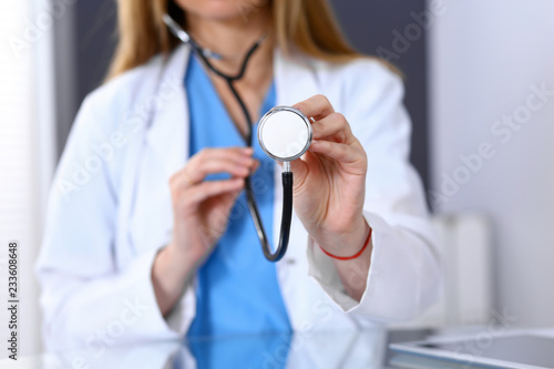 Doctor holds stethoscope head, close-up. Medical help and insurance in health care, best treatment and medicine concept. Blue tone of picture