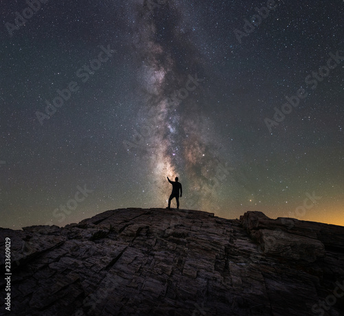 A silhouette of a man reaching for the stars of the Milky Way Galaxy 
