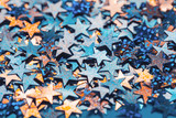Orange and blue star shaped festive confetti background close up