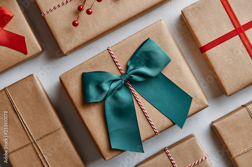 Christmas presents wrapped in brown paper and decorated with bows and ribbons. From above