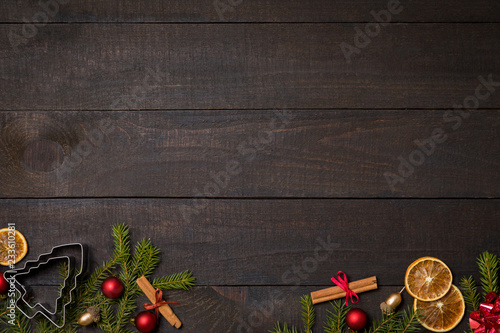 Dark rustic wooden table background with Christmas decoration and fir frame. Top view with free space for copy text