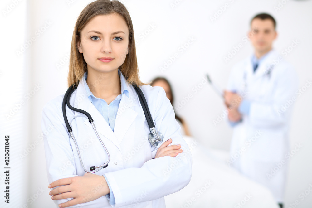 Medicine doctor standing and smiling on the background with patient in the bed Medicine doctor standing and smiling on the background with patient in the bed