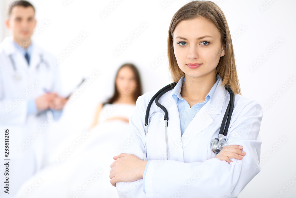 Medicine doctor standing and smiling on the background with patient in the bed Medicine doctor standing and smiling on the background with patient in the bed