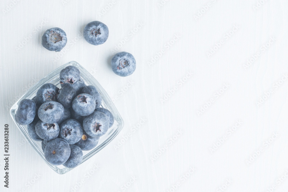 Fresh blueberries in a glass cup on a light background, top view