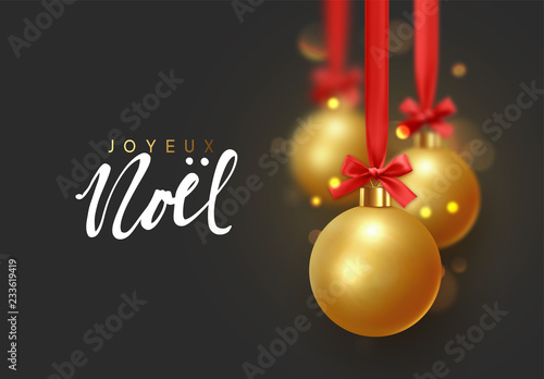 French text Joyeux Noel. Christmas background with balls hanging on ribbon with bows and bright sparkling bokeh lights.