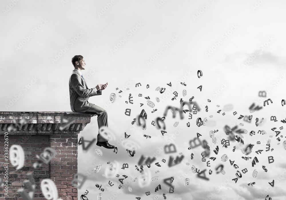 Man on roof edge send message with smartphone and symbols flying Man on roof edge send message with smartphone and symbols flying