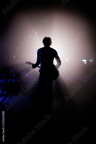 Rear view of man playing guitar at concert