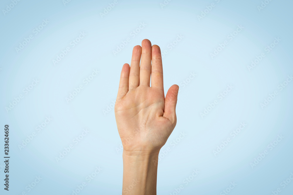 Female palm raised up on a blue background. Stop gesture. Concept stop someone, warn Female palm raised up on a blue background. Stop gesture. Concept stop someone, warn