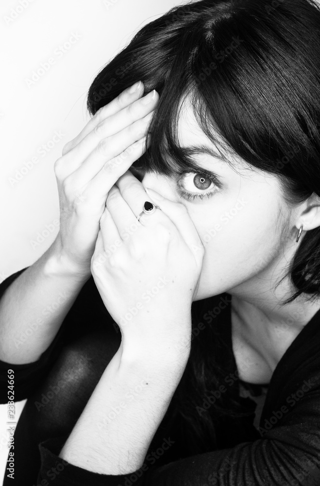 Fototapeta premium Attractive young woman hides her face behind her hands