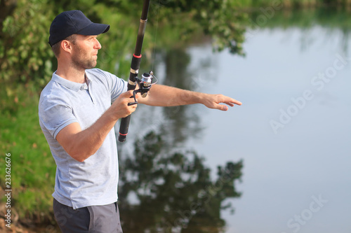 Fisherman with fishing rod on river bank