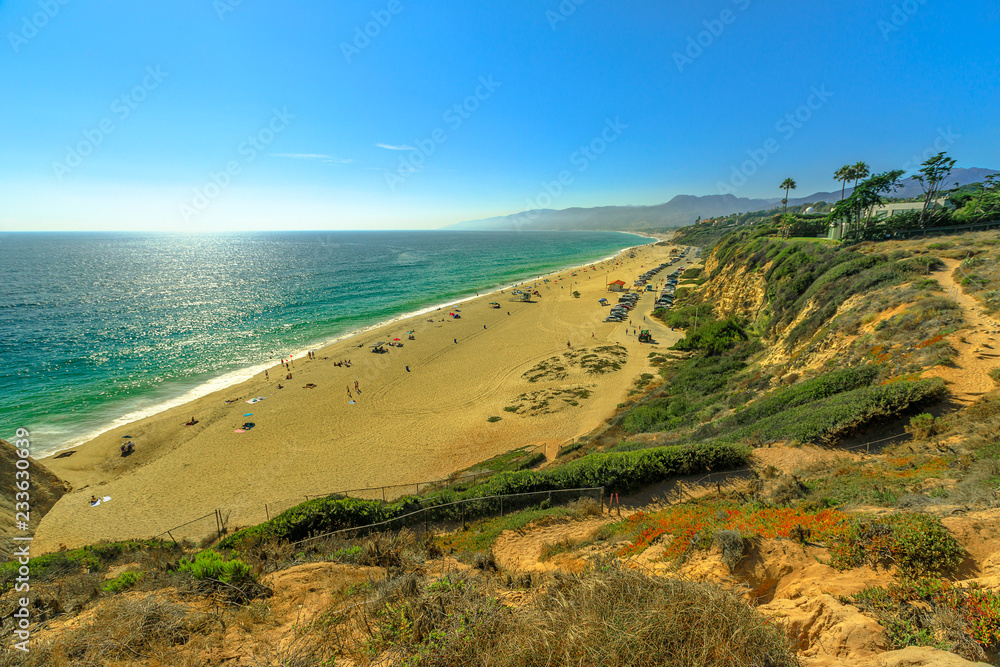 Aerial view of scenic Point Dume State Beach from Point Dume promontory on Malibu coast, Pacific Ocean in CA, United States. California West Coast. Blue sky, summer sunny day. Copy space. Aerial view of scenic Point Dume State Beach from Point Dume promontory on Malibu coast, Pacific Ocean in CA, United States. California West Coast. Blue sky, summer sunny day. Copy space.