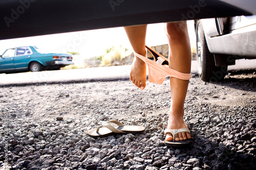Canvas Print Low section of woman removing panty while standing by car