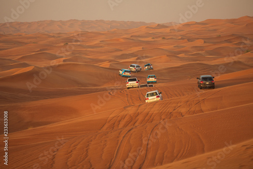 Off-road adventure with SUV driving in Arabian Desert at sunset. Offroad vehicle bashing through sand dunes in Dubai desert. Traditional entertainment for tourists
