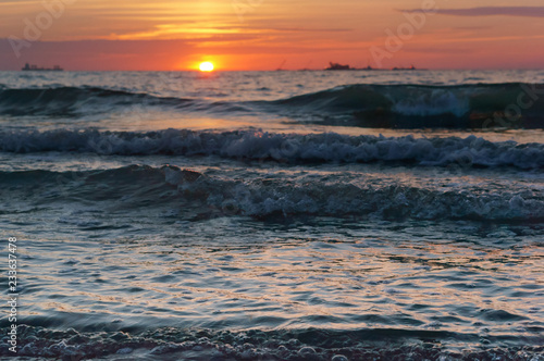 Sunset over the sea. Reflection of sunlight in the sea waves. Red and yellow sky in the rays of the sunset.