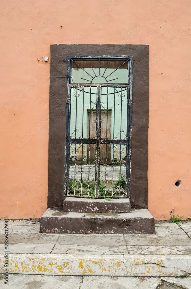 Fototapeta premium old wooden door with rusty bars on a wall old and broken, space for texts.