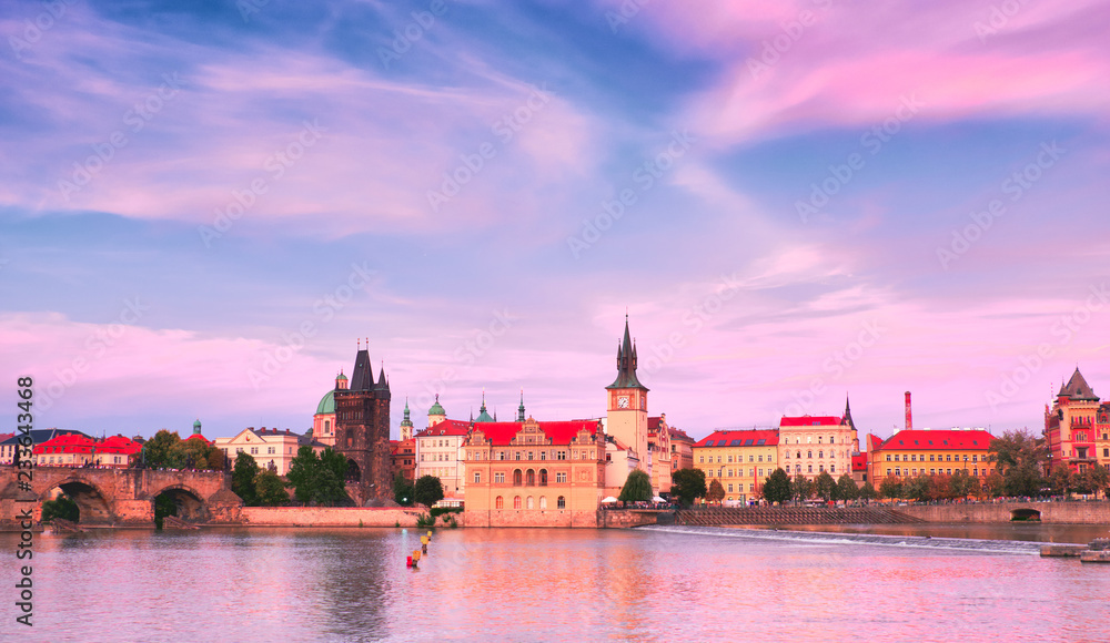 Prague, riverside on sunset, with Charles Bridge on the right and historic skyline in front