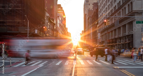 Busy New York City street scene with crowds of people in Midtown Manhattan with sunset background