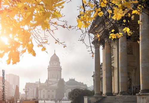 Yellow marple leaves and classical architecture of Gendarmenmarkt on a misty day in Berlin