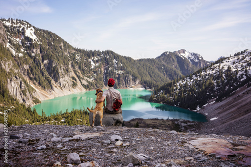 Canvas Print Rear view of man sitting with dog against mountain
