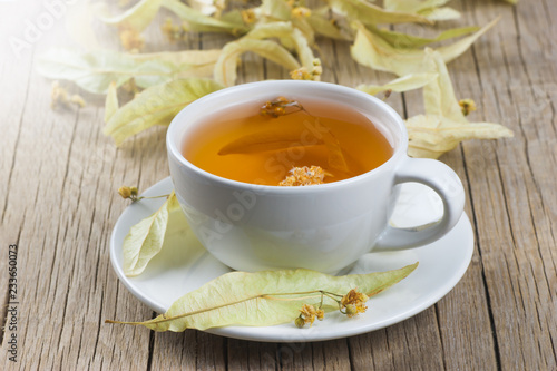 white cup linden tea or blooming tilia, basswood, on rustic vintage wooden table. Herbal tea concept, selective focus 