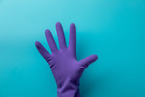 A gloved hand shows five fingers on a blue background. Blue latex glove on the hand of a doctor or cleaner