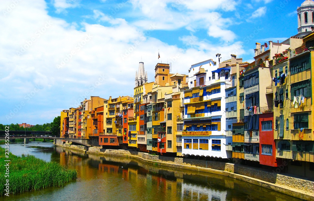 Colorful yellow and orange houses  reflected in water river , in Girona, Catalonia, Spain. Church Saint Mary Cathedral at background