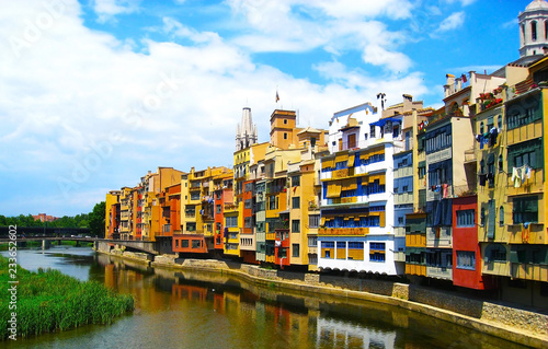 Colorful yellow and orange houses reflected in water river , in Girona, Catalonia, Spain. Church Saint Mary Cathedral at background